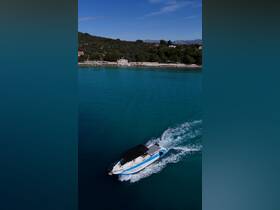 A stunning aerial view of a speedboat cruising through crystal-clear turquoise waters, surrounded by lush greenery and coastal scenery.