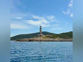 A stunning view of a lighthouse perched on a rocky coastline, surrounded by lush greenery and sparkling waters — a perfect representation of coastal beauty.