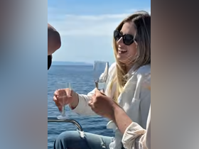 A joyful moment aboard a boat as a woman raises her glass in celebration, perfect for capturing the essence of fun and camaraderie on the water.