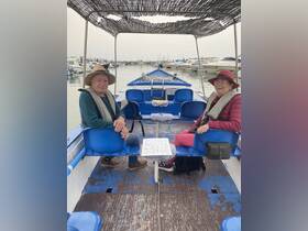 A cozy interior view of a boat featuring two guests seated comfortably, showcasing the relaxed atmosphere perfect for a day on the water.