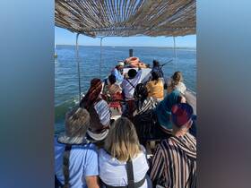 A lively group enjoys an entertaining boat ride, with a performer engaging guests in a unique experience on the water.