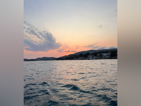 A stunning sunset view over the coastline, capturing the serene beauty of the water and surrounding hills — perfect for those seeking picturesque moments on their boating adventures.