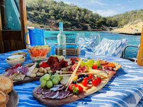 A beautifully arranged charcuterie board with a variety of snacks and drinks, perfect for enjoying a relaxing day on the water.