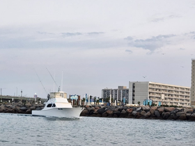 A sleek yacht navigates through calm waters, showcasing its elegant design as it approaches the harbor — perfect for fishing trips or leisurely cruises.