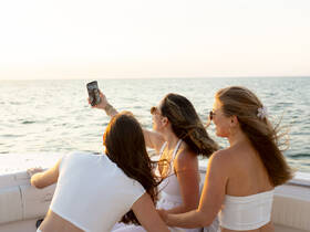 A group of friends captures a fun selfie on a boat during sunset, celebrating their time on the water with laughter and joy.