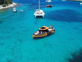 A lively group enjoys a day on the water aboard a stylish boat, surrounded by stunning turquoise waters — perfect for summer adventures and relaxation.