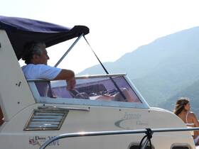 A serene moment on the water with a captain at the helm and a guest enjoying the view, showcasing the beauty of boating adventures.