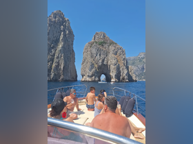 A lively group enjoys a scenic boat ride near iconic rock formations, creating unforgettable memories in a stunning coastal landscape.