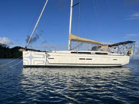 A stunning side view of a yacht docked in calm waters, showcasing its sleek design against a backdrop of blue skies and lush greenery.