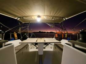 A cozy view of the interior cabin of a sailboat at night, featuring a well-lit dining area and a serene atmosphere perfect for evening relaxation on the water.