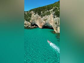 A scenic view of a boat cruising through crystal-clear turquoise waters near a stunning rocky coastline, perfect for exploring beautiful marine landscapes.