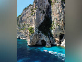 A scenic view of a boat navigating through stunning turquoise waters near dramatic cliffs, showcasing the beauty of coastal adventures.
