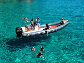 A lively group enjoys a day on the water, with some swimming and others relaxing on a boat in crystal-clear waters — perfect for summer adventures and family outings.