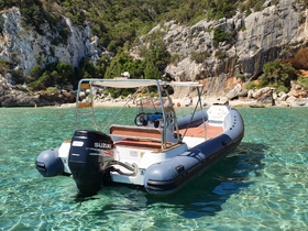 A sleek speedboat anchored in crystal-clear waters, surrounded by stunning rocky cliffs — perfect for exploring secluded beaches.