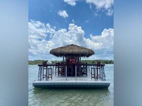 A picturesque tiki boat with a thatched roof, anchored in calm waters under a bright blue sky — perfect for leisurely outings and gatherings.