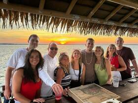 A cheerful group enjoys a sunset celebration with drinks, capturing the perfect moment on the water — ideal for memorable gatherings and special occasions.