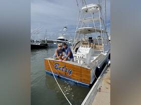 A cheerful couple poses on the back of their fishing boat named 'Betsy' at the dock, showcasing a perfect day on the water.