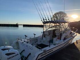 A beautiful fishing boat named 'HERE WE GO' docked peacefully at sunrise, showcasing its sleek design and fishing gear, perfect for a day on the water.