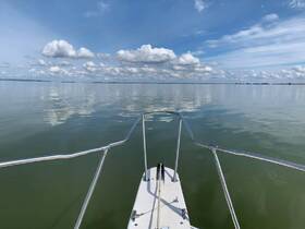 A serene view from the front of a boat, showcasing calm waters and a beautiful sky filled with clouds — perfect for a peaceful day on the water.