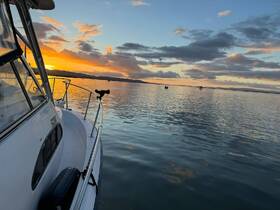 A stunning sunset view from the front of a yacht, showcasing calm waters and a serene atmosphere — perfect for evening cruises.