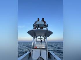 Two men enjoy a day on the water, piloting their boat under a clear blue sky — perfect for fishing adventures or leisurely cruises.