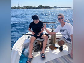 Two friends enjoy a fishing trip on a boat, showcasing the excitement of catching fish in the open ocean — a perfect day for adventure on the water.