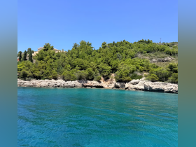 A stunning view of a lush coastline with crystal-clear turquoise waters, perfect for exploring by boat or enjoying a relaxing day at the beach.