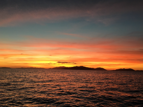 A breathtaking sunset over the tranquil waters, with silhouetted islands in the background — a perfect scene for romantic evenings or peaceful boat rides.