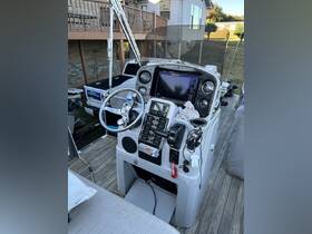 A detailed view of the helm and console area of a boat, showcasing the steering wheel, controls, and seating — perfect for navigating the waters.