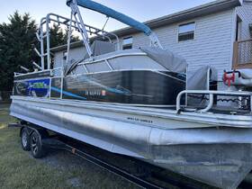 A sleek pontoon boat, Angler Quest, showcased in a side view while docked, perfect for leisurely outings on the water.