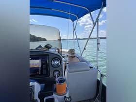 A cozy interior view of a pontoon boat's helm, featuring a guest relaxing in the seating area while enjoying the scenic waters.
