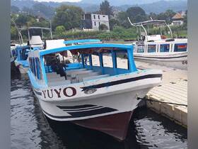 A close-up view of the 'Yuyo' boat docked at the pier, showcasing its vibrant blue and white design, perfect for exploring local waterways.