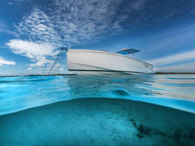 A stunning view of a sleek yacht anchored in crystal-clear waters, showcasing the boat's elegant design against a backdrop of a vibrant sky.