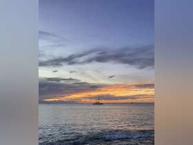 A serene sunset view featuring a catamaran anchored in calm waters, perfect for capturing the beauty of evening boat outings.