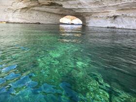 A stunning view of a natural cave with crystal-clear waters, showcasing the beauty of the coastline — perfect for exploring hidden gems on a boat trip.