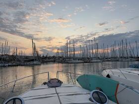 A serene sunset view from the bow of a yacht, overlooking a marina filled with sailboats — perfect for capturing the tranquility of evening on the water.
