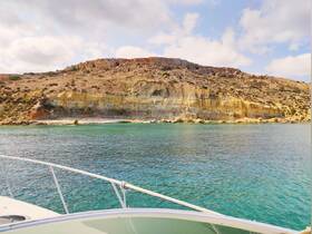 A stunning view of a rocky coastline from the deck of a boat, showcasing the beautiful turquoise waters and natural landscape — perfect for scenic boat tours.