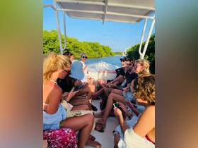 A lively group enjoys a boat ride through mangroves, capturing moments on their phones while soaking in the beautiful surroundings.