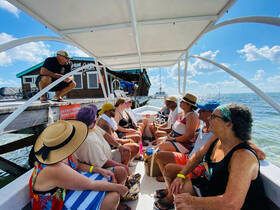 A lively group enjoys a boat tour, engaging with their guide while soaking up the sun and beautiful scenery — perfect for memorable adventures on the water.