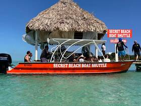 A lively group boards the Secret Beach Boat Shuttle, ready for an exciting beach excursion in crystal-clear waters.