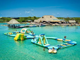 A vibrant scene of guests enjoying inflatable water activities in a beautiful lagoon, perfect for family fun and summer adventures.