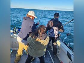 A group of friends enjoys a fishing trip on the open water, showcasing the excitement of reeling in a catch together.