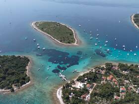 A stunning aerial view of a picturesque coastline with multiple boats anchored in clear turquoise waters, showcasing the beauty of island destinations.