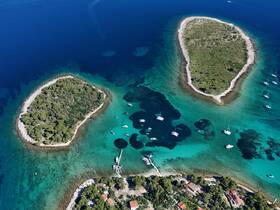 A stunning aerial view of two lush islands surrounded by crystal-clear turquoise waters, showcasing the beauty of the coastline and ideal for exploring by boat.