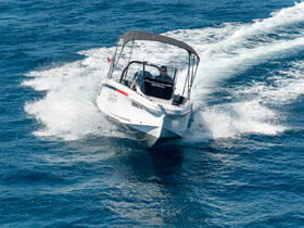 A sleek speedboat cuts through the vibrant blue waters, showcasing its dynamic design and performance on the open sea.