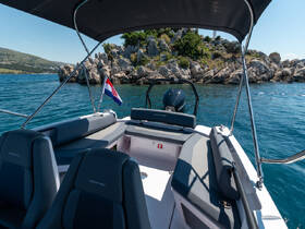 A view of the interior seating and helm of a modern boat, showcasing a comfortable space for passengers while enjoying the scenic coastal surroundings.
