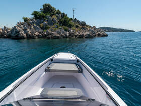 A sleek speedboat is anchored near a rocky island, showcasing the tranquil blue waters and clear skies — perfect for a day of exploration and adventure.