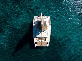 A stunning aerial view of a catamaran gliding over crystal-clear waters, showcasing its sleek design and tranquil surroundings — perfect for luxury sailing adventures.