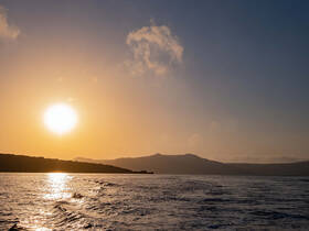 A stunning sunset over a tranquil coastline, showcasing the beauty of the sea and sky — perfect for serene evening boat rides.