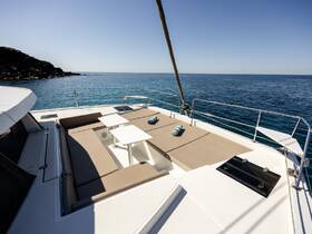 A spacious lounge area on a yacht, featuring comfortable seating and tables, perfect for relaxing while enjoying the serene ocean views.